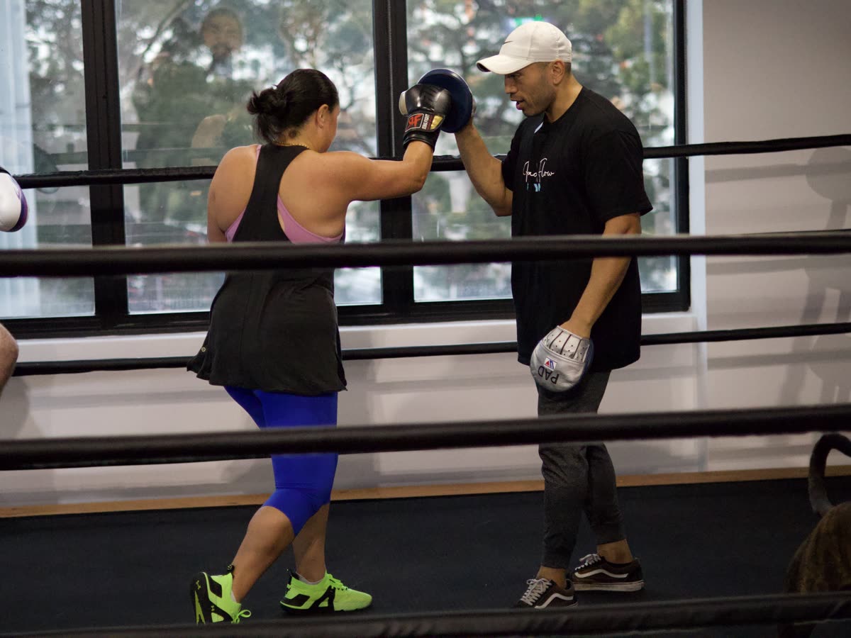A Pad Flow coach helping a beginner learn boxing fundamentals